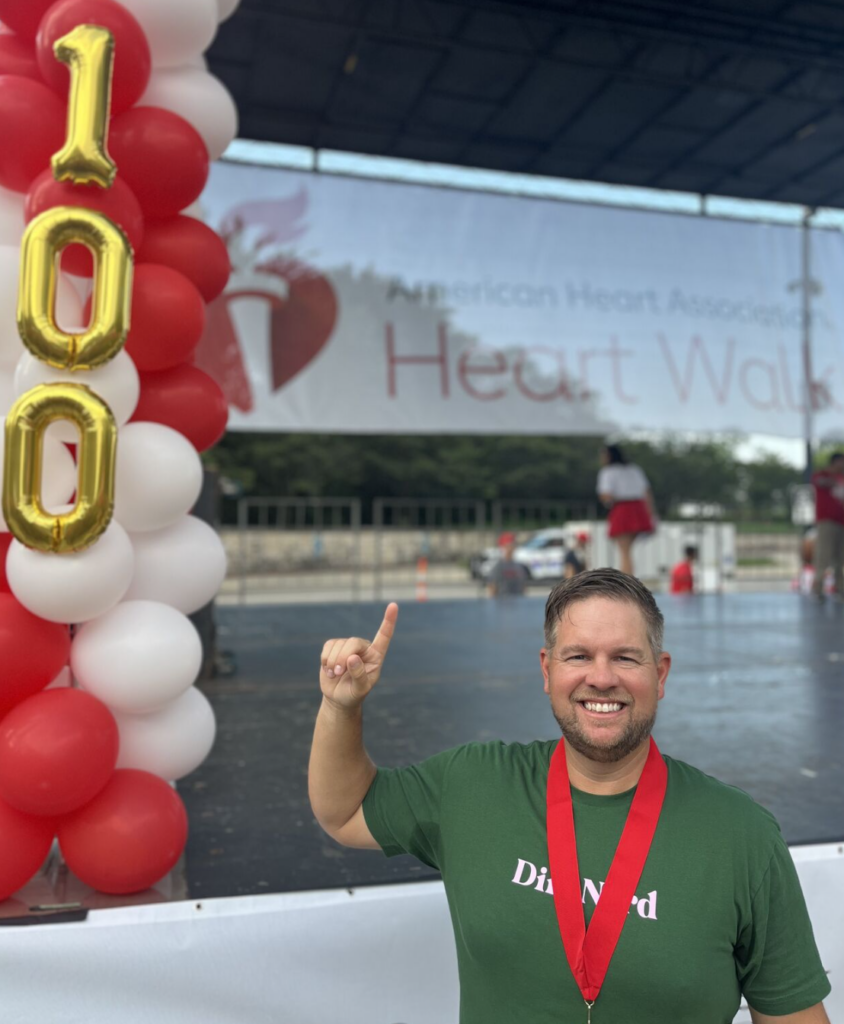 Person holding up a #1 sign in front of balloons that say 100